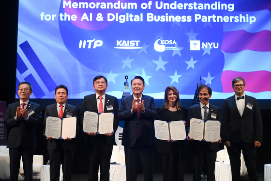 Korean President Yoon Suk Yeol, center, claps during a commemorative photo taken with New York University President Linda Mills, third from right, and the heads of KAIST, the Korea Software Industry Association and the Institute for Information Communication Technology Planning and Evaluation at New York University on Thursday. The three Korean institutions signed a memorandum of understanding on an AI and digital business partnership with New York University that day. [JOINT PRESS CORPS]