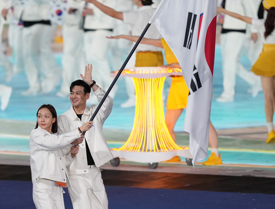 Flag bearers Kim Seo-yeong, left, and Gu Bon-gil parade into the Hangzhou Olympic Sports Center Stadium during the opening ceremony of the 19th Asian Games in Hangzhou, China on Saturday. [XINHUA] 
