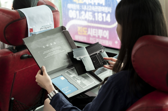 Visitors of the Folk Music Route of Korea look through their tourist kits from inside a bus taking them to locations on the route. [KOREA CULTURAL HERITAGE FOUNDATION]