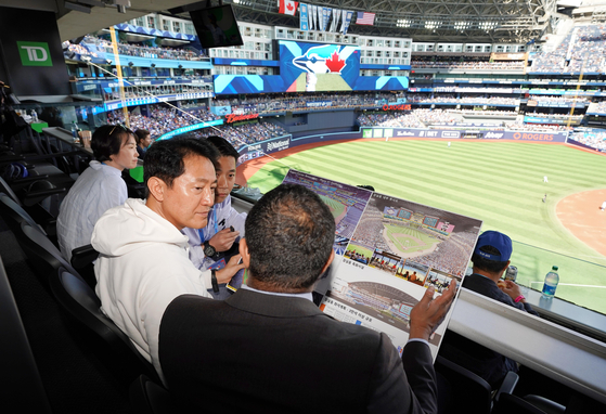 Seoul Mayor Oh Se-hoon, left, learns about the Rogers Centre in Toronto from Anuk Karunaratne, the executive vice president for business operations for the Toronto Blue Jays, at a private box on Saturday. [SEOUL METROPOLITAN GOVERNMENT]