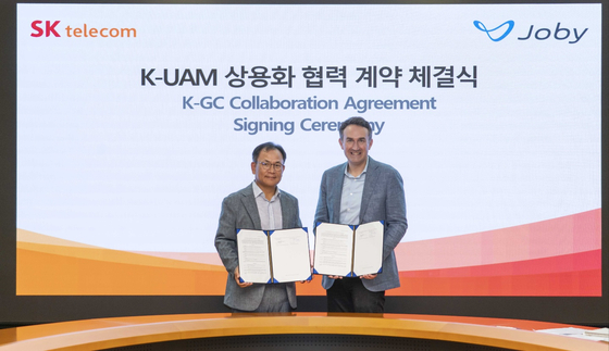 Ha Min-yong, chief development officer, SK Telecom, left, and Eric Allison, head of product at Joby Aviation, poses for a photo after signing a partnership agreement at SK Telecom's headquarters in Jung District, central Seoul, on Wednesday. [SK TELECOM]