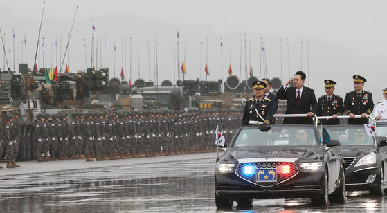 President Yook Suk Yeol, standing right, conducts a military review in a car during a ceremony to mark the 75th anniversary of Armed Forces Day at Seoul Air Base in Seongnam, Gyeonggi, Tuesday. [JOINT PRESS CORPS]