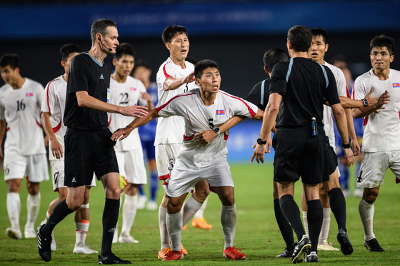 North Korea's Kim Kyong-sok, center, rounds on referee Rustam Lutfullin during a men's quarterfinal match between North Korea and Japan at the Hangzhou Asian Games in Hangzhou, China on Sunday.  [AFP/YONHAP]