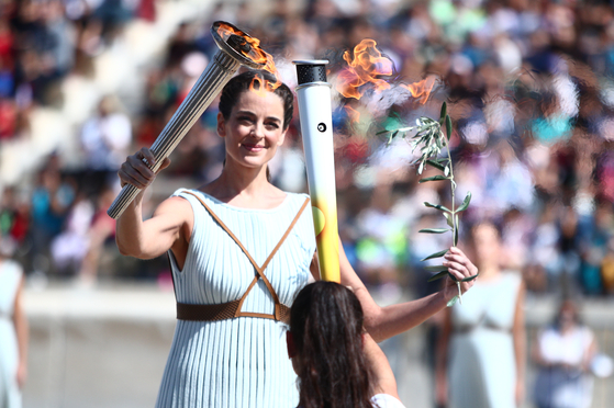 The Olympic flame is passed to the 2024 Gangwon Youth Olympics torch at the Panathenaic Stadium in Athens.  [HELLENIC OLYMPIC COMMITTEE]