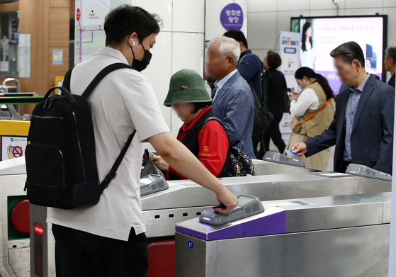 Passengers pass through subway turnstiles at Gwanghwamun Station in central Seoul on Tuesday. [NEWS1] 