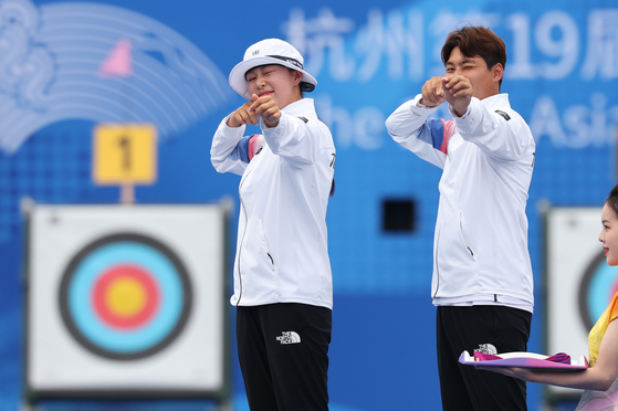 Korea's Lim Si-hyeon, left, and Lee Woo-seok celebrate on the podium after beating Japan in the final to take the mixed team recurve archery gold medal at the Hangzhou Asian Games in Hangzhou, China on Wednesday.   [NEWS1]
