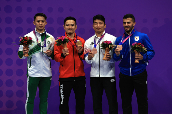 Gold medallist Japan's Kazumasa Moto, center, poses with silver medallist Macau's Kuok Kin Hang, left, and bronze medallists Korea's Park Hee-jun, second from right, and Kuwait's Sayed Salman Al Mosawi during the medal ceremony for the men's karate kata contest at the Hangzhou Asian Games in Hangzhou China on Thursday.  [REUTERS/YONHAP]