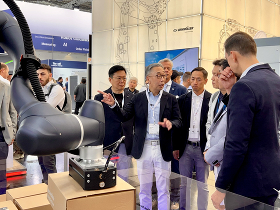 Park Ji-won, vice chairman of Doosan, second from the left, talks at the Automatica booth after observing the performance of a collaborative robot manufactured by Doosan Robotics in Munich, Germany. [DOOSAN]