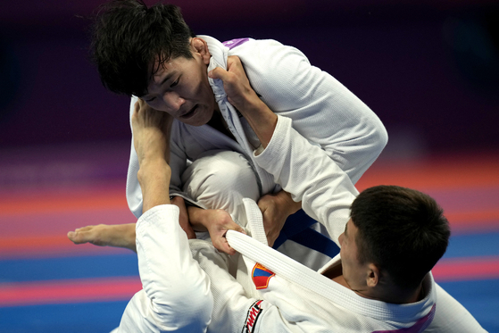Korea's Joo Seong-hyeon defeats Mongolia's Tuvdentarvaa Choijamts to take bronze in the men's ju-jitsu -69 kilograms contest on Thursday. [REUTERS/YONHAP] 