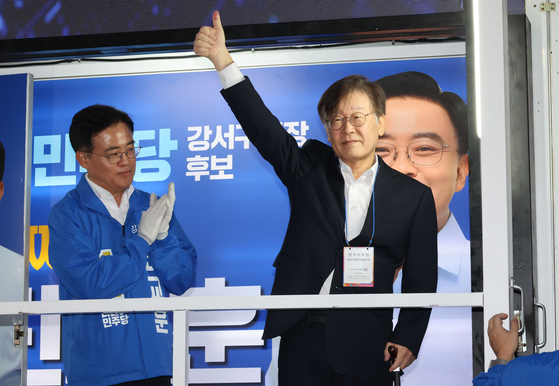 Democratic Party (DP) Chairman Lee Jae-myung, right, takes part in campaigning at Gangseo District, western Seoul, Monday for Jin Kyo-hoon, left, DP's candidate for the by-election on Wednesday to select the new head of Gangseo District Office. Jin is up against the People Power Party’s candidate Kim Tae-woo. [YONHAP]