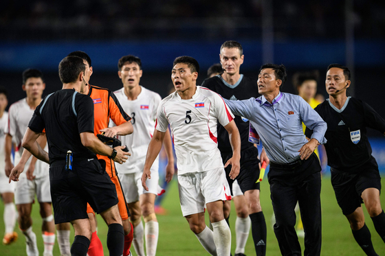 North Korea's Kim Kyong-sok, center, rounds on referee Rustam Lutfullin during a men's quarterfinal match between North Korea and Japan at the Hangzhou Asian Games in Hangzhou, China on Sunday. [AFP/YONHAP]