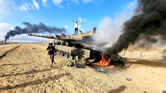 Palestinians celebrate by a destroyed Israeli tank at the Gaza Strip fence east of Khan Yunis southern on Saturday. [AP/YONHAP]