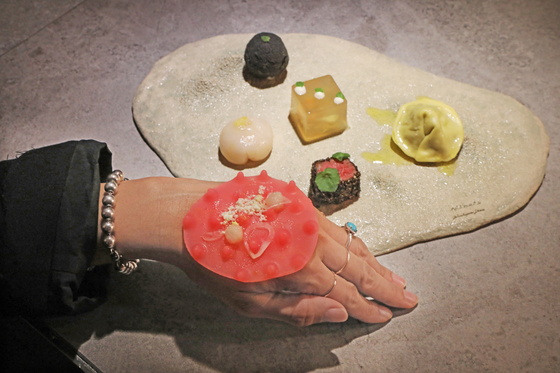 A special dish at Level: 0, intended to trigger various senses and "disturb the brain." It is comprised of a slice of beef steak, a scallop, a mushroom dumpling, vegetable pâté and a butter ball. The twist here is that a bumpy silicon flap is placed on the back of one’s hand. It is sprinkled with a seasoned powder, which guests are instructed to suck on as a palate cleanser. [PARK SANG-MOON]