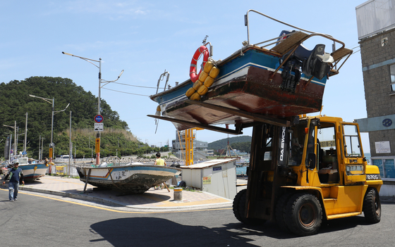 A forklift lifts a boat. The forklift truck is moving the boat to land. [NEWS1]