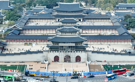 Workers take down the old signboard from the main entrance to Gyeongbok Palace on Thursday. Along with the new signboard, the newly restored “moon terrace” will be unveiled on Sunday. [YONHAP]
