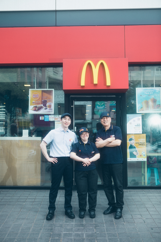McDonald’s staff members take a picture in front of one of the company’s restaurants. [MCDONALD'S KOREA] 