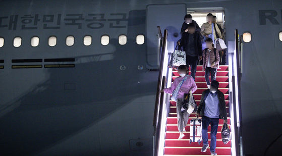 Koreans that were evacuated from Israel walks down the stairs from the military aircrraft KC-330 at the Seoul Air Base in Gyeonggi on Saturday. The passengers also included 51 Japanese and 6 Singaporeans. [JOINT PRESS CORPS]