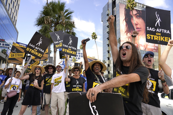 SAG-AFTRA member John Schmitt, second from right, and others carry signs on the picket line outside Netflix on Wednesday, Sept. 27, 2023, in Los Angeles. [AP=YONHAP]