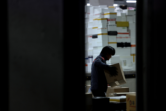 A delivery worker sorts parcels at the Seoul Southeast Logistics Center. [YONHAP]