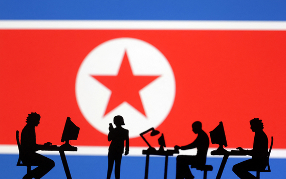 Miniatures of people with computers are seen in front of a North Korea flag in this illustration made on July 19. [REUTERS/YONHAP]