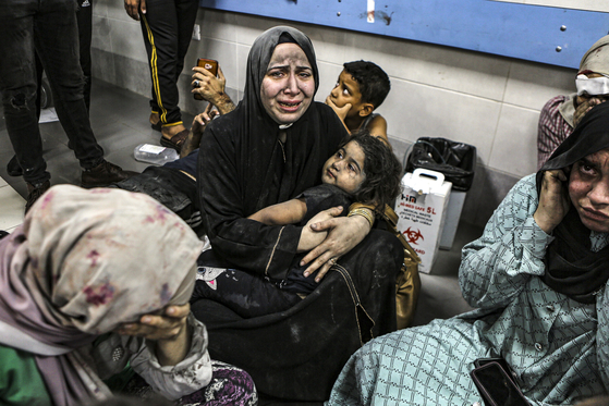 Wounded Palestinians sit on the floor at the al-Shifa hospital, in Gaza City, central Gaza Strip, on Tuesday. [AP/YONHAP]