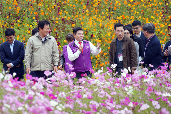 The head of Dongdaemun District Office Lee Pil-hyeong, center, introduces a temporary flower garden in Jeonnong-dong, a site for the district's future public library, to reporters during a press tour held on Thursday. [DONGDAEMUN DISTRICT OFFICE]