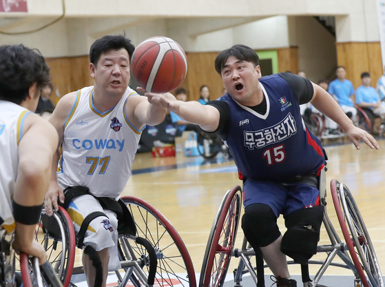 Coway's Kang Hee-joon, left, intercepts Mugunghwa's Han Hee-seok's ball at a game of the 2023 KWBL Wheelchair Basketball League in October. [YONHAP]