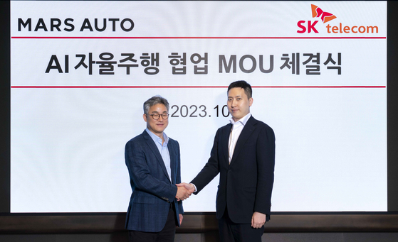 SK Telecom's Chung Seok-geun, the head of the company's global and AI tech business unit, left, and Mars Auto's Chief Operating Officer Roh Jae-kyoung, pose for a photo after signing a partnership at SK Telecom's office building in Jung District, central Seoul. [SK TELECOM]