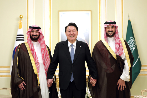 President Yoon Suk Yeol holds hands with Saudi Minister of National Guard Abdullah bin Bandar Al Saud, left, and Saudi Minister of Defense Khalid bin Salman Al Saud, right, for a commemorative photo in Riyadh on Monday. [JOINT PRESS CORPS]