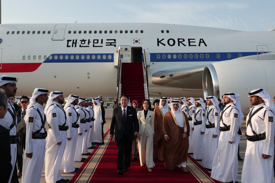 President Yoon Suk Yeol, left, and first lady Kim Keon Hee, center, are greeted by Qatari officials and an honor guard as they arrive at Hamad International Airport near Doha on the presidential jet Tuesday for a two-day state visit. [JOINT PRESS CORPS]