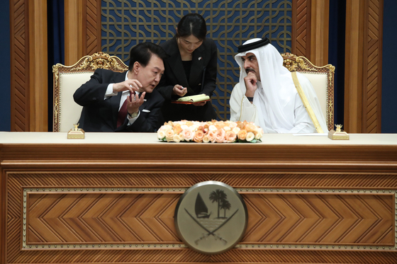 President Yoon Suk Yeol, left, speaks with Qatar's Emir Tamim bin Hamad Al Thani at a ceremony for signing memorandums of understanding during their bilateral summit at the Amiri Diwan palace in Doha on Wednesday. This marks the first state visit by a Korean president to Qatar. [JOINT PRESS CORPS]