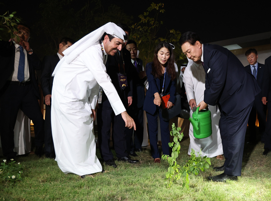 President Yoon Suk Yeol, right, waters a tree gifted by the Qatari emir as he attends the opening ceremony of the Korean pavilion at the 2023 International Horticultural Exposition in Doha Tuesday after arriving in Qatar for a state visit. [JOINT PRESS CORPS]