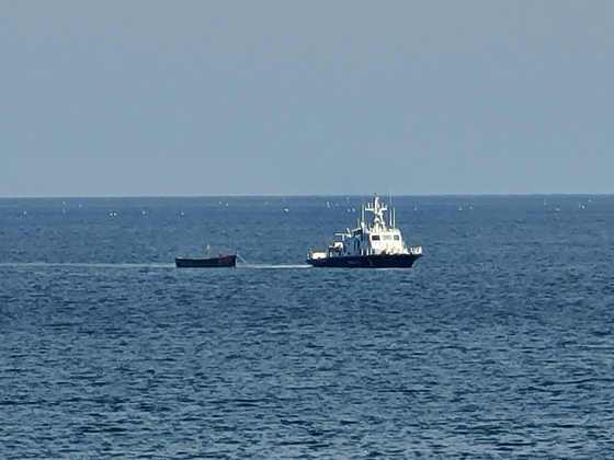 A wooden boat that is believed to have carried four North Koreans who defected to South Korea on Tuesday is being towed by a Korea Coast Guard patrol boat near Yangyang County, Gangwon, on the same day. [YONHAP]