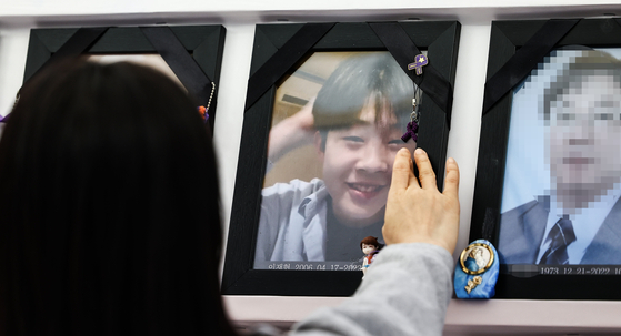 The mother of a victim of the Itaewon crowd crush touches a photo of her son at a memorial altar in front of Seoul City Hall [JOONGANG PHOTO]