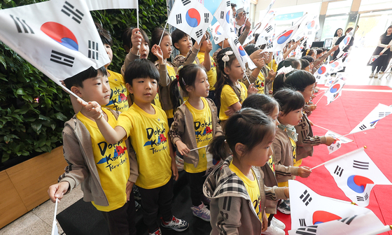 Kindergarteners wearing Dokdo Island T-shirts wave the Korean national flag at the Dalseo Arts Center in Daegu on Wednesday to celebrate Dokdo Day, which falls on Oct. 25. Dokdo Day was named by a non-profit organization in 2000. [YONHAP]