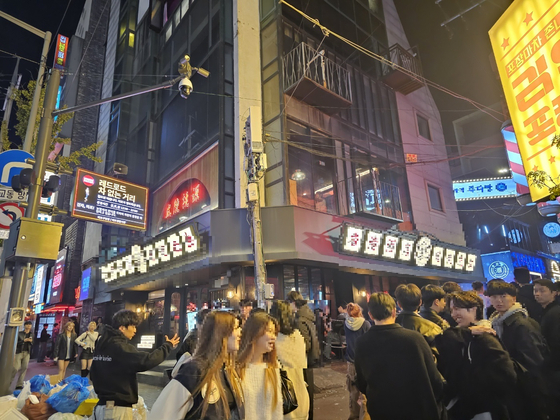 An ″intelligent″ CCTV hangs above a the street in Hongdae, a popular nightlife area in Mapo District, western Seoul. The CCTV can broadcast an alert when it detects a potential crowd crush. [LEE CHAN-KYU]
