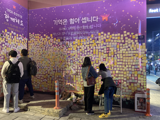 Visitors on Wednesday write and post messages to those who lost their lives during the deadly crowd crush in Itaewon on a wall next to the alleyway where the tragedy occurred. [CHO JUNG-WOO] 