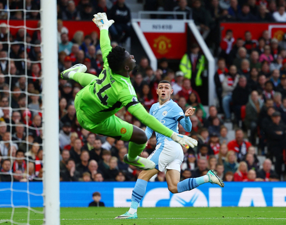 Manchester United's Andre Onana saves a shot from Manchester City's Phil Foden during a match at Old Trafford in Manchester on Sunday.  [REUTERS/YONHAP]