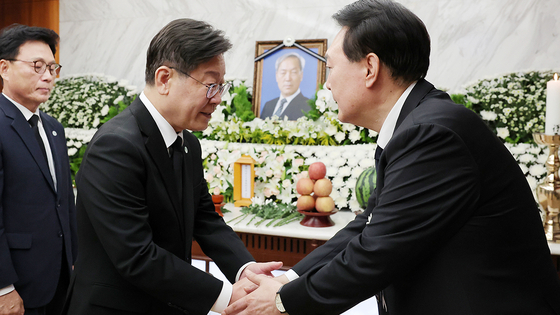 Democratic Party leader Lee Jae-myung, left, shakes hands with President Yoon Suk Yeol after paying condolences for his late father, Yoon Ki-jung, a professor emeritus of Yonsei University, at Severance Hospital in Seodaemun District, western Seoul, on Aug. 15. [PRESIDENTIAL OFFICE]