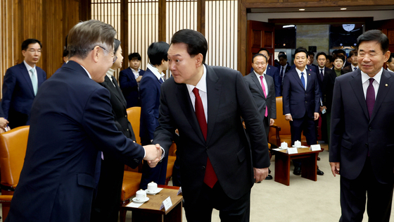 President Yoon Suk Yeol, right, shakes hand with Democratic Party’s leader Lee Jae-myung at the National Assembly speaker’s office in Yeouido, Seoul, before making his speech on next year’s budget on Monday. [YONHAP]