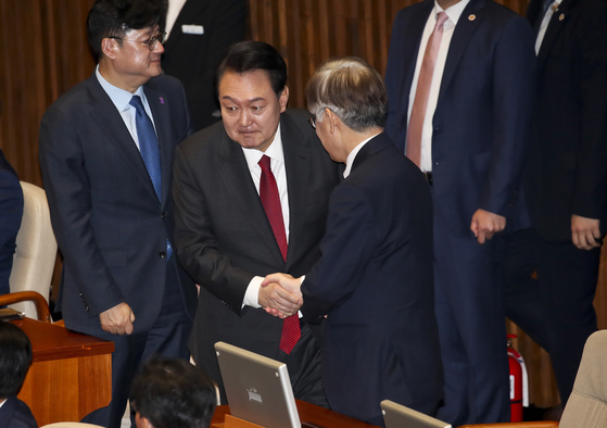 President Yoon Suk Yeol, left, shakes hand with Democratic Party Chairman Lee Jae-myung before making a parliamentary speech on next year’s budget at the National Assembly in Yeouido, western Seoul, on Tuesday. [JOINT PRESS CORPS]