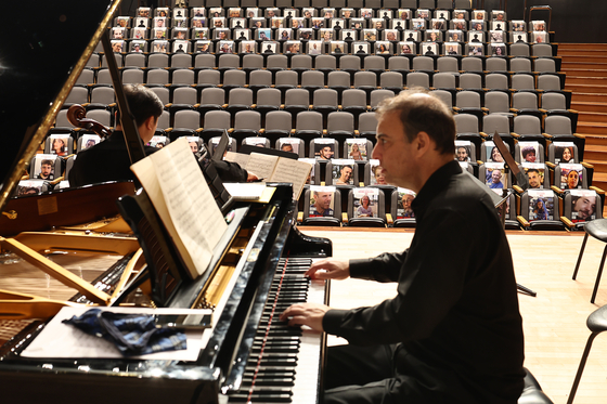 A pianist rehearses at Seoul National University's concert hall in Seoul during a recital on Wednesday in front of seats filled with pictures of the 240 people believed to have been taken hostage during an attack by the militant group Hamas on Israel on Oct. 7. The Israel Embassy in Seoul hosted the “Concert of the Missing” to stand in solidarity with the hostages and their families and to demand the immediate and unconditional release of all hostages. [YONHAP] 