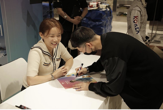Olympian Nam Hyun-hee at an autograph signing ceremony at Hyundai Department Store in Pangyo, Gyeonggi, in August. The person wearing black has been speculated to be Nam's ex-fiance Jeon Cheong-jo, who claimed to be a family of the hotel and casino group, Paradise. [NAM HYUN-HEE INSTAGRAM]