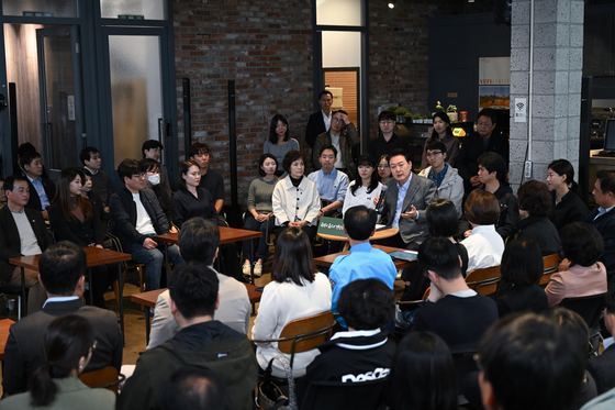 President Yoon Suk Yeol, center right, speaks at a town hall meeting on the economy and public livelihood with 60 people from all walks of life at a cafe in Mapo District, western Seoul, on Wednesday. [PRESIDENTIAL OFFICE]
