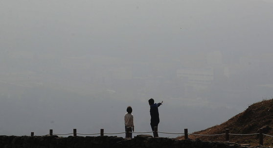 Two people look down on the city of Osan in Gyeonggi from Bojeok Temple as thick fine dust engulfs the area on Tuesday. [NEWS1] 
