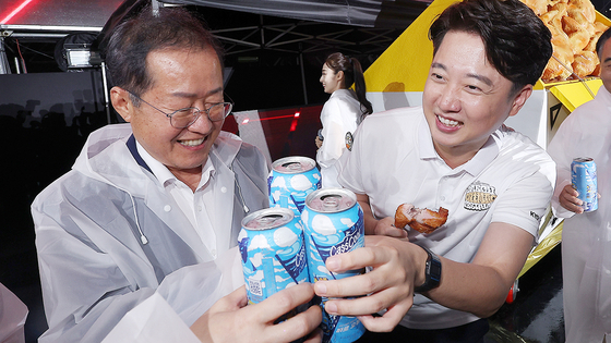 Former People Power Party (PPP) chief Lee Jun-seok, right, and Daegu Mayor Hong Joon-pyo attend the opening ceremony of a chicken and beer festival in Daegu on Aug. 30. The PPP restored their party memberships Thursday as a part of its innovation committee’s efforts to integrate the party. [YONHAP]