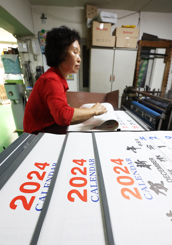 A member of staff at a print shop in Suwon, Gyeonggi is printing out new calendars for 2024 on Thursday. [YONHAP]