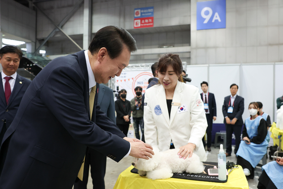 President Yoon Suk Yeol touches a poodle at the Pet Industry Association's booth at the small business convention at Kintex exhibition hall in Goyang, Gyeonggi, on Friday. [PRESIDENTIAL OFFICE] 