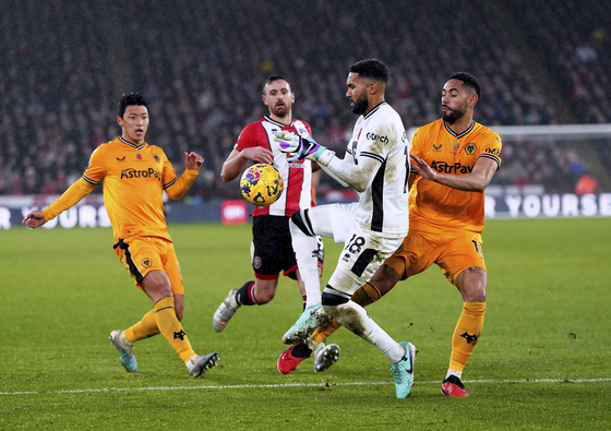 Sheffield United goalkeeper Wes Foderingham, center right, Wolverhampton Wanderers' Matheus Cunha, right, and Hwang Hee-chan, left battle for the ball, during a Premier League match at Bramall Lane in Sheffield, England on Saturday.  [AP/YONHAP]