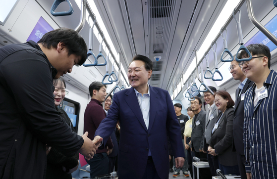 President Yoon Suk Yeol, center, greets commuters who travel in and out of the metropolitan area aboard a GTX-A train at Dongtan Station in Hwaseong, Gyeonggi, on Monday. The GTX-A train route will make an initial launch next March. [JOINT PRESS CORPS]